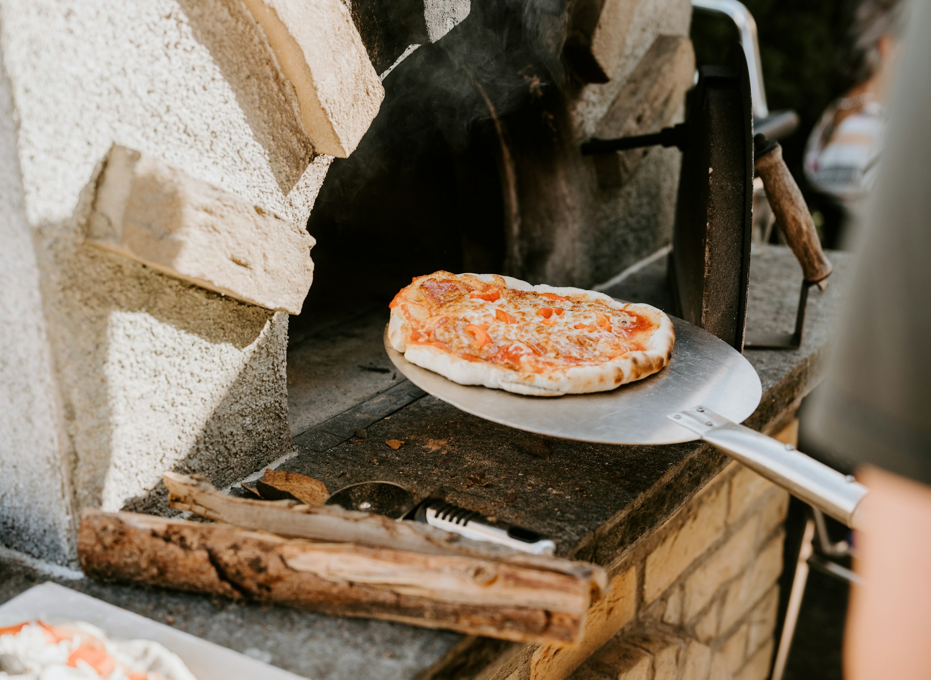 A pizza is being removed from a wood-fired oven.